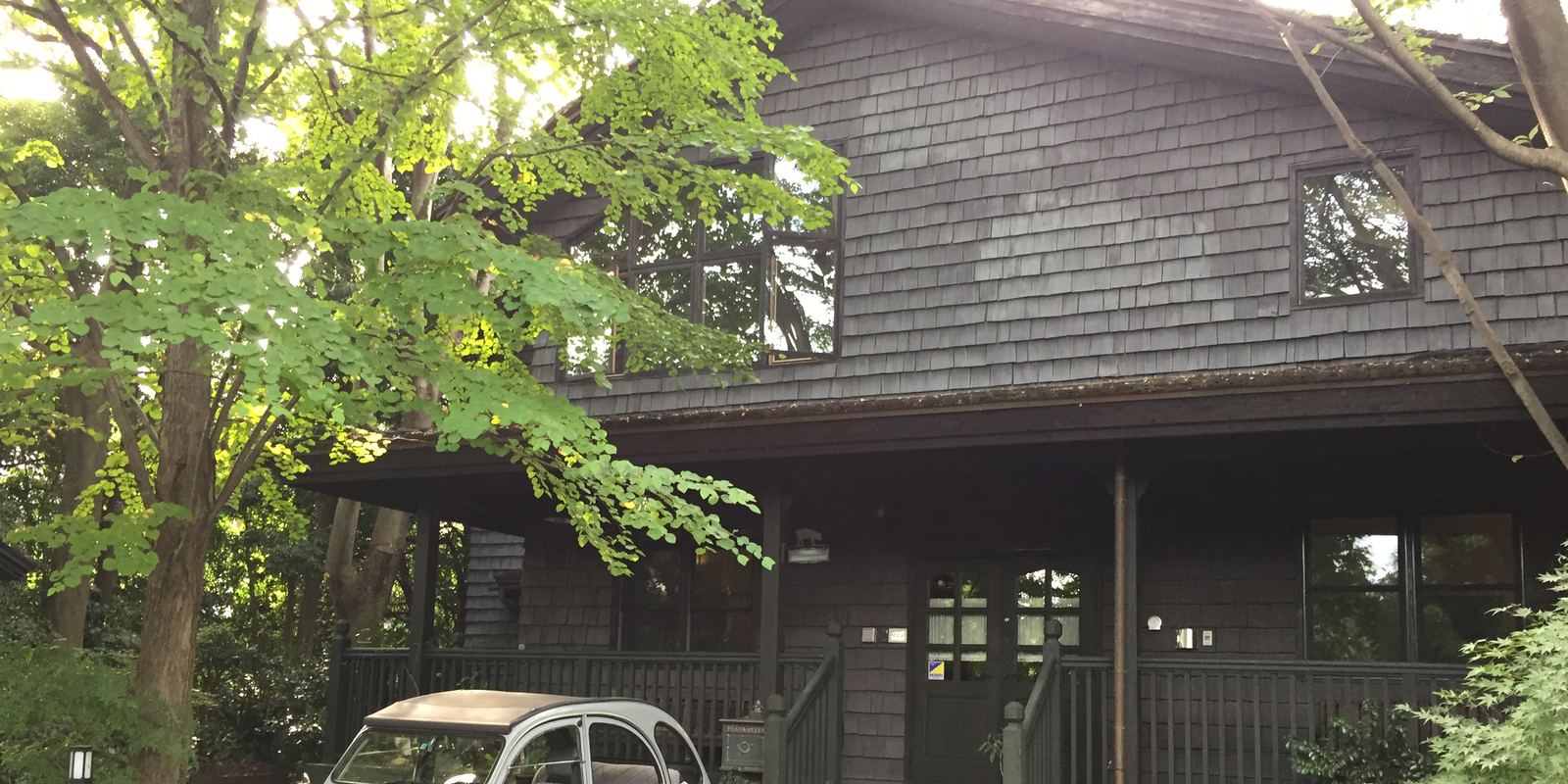 Hayao Miyazaki's small wooden personal studio building in Tokyo with a classic car parked outside