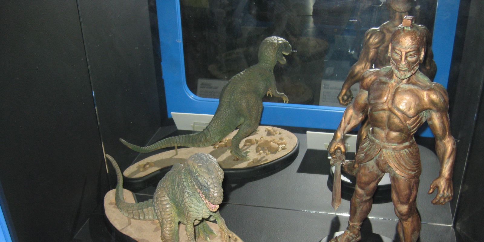 Stop-motion models of an allosaurus and a bronze giant made by Ray Harryhausen, on display in a museum